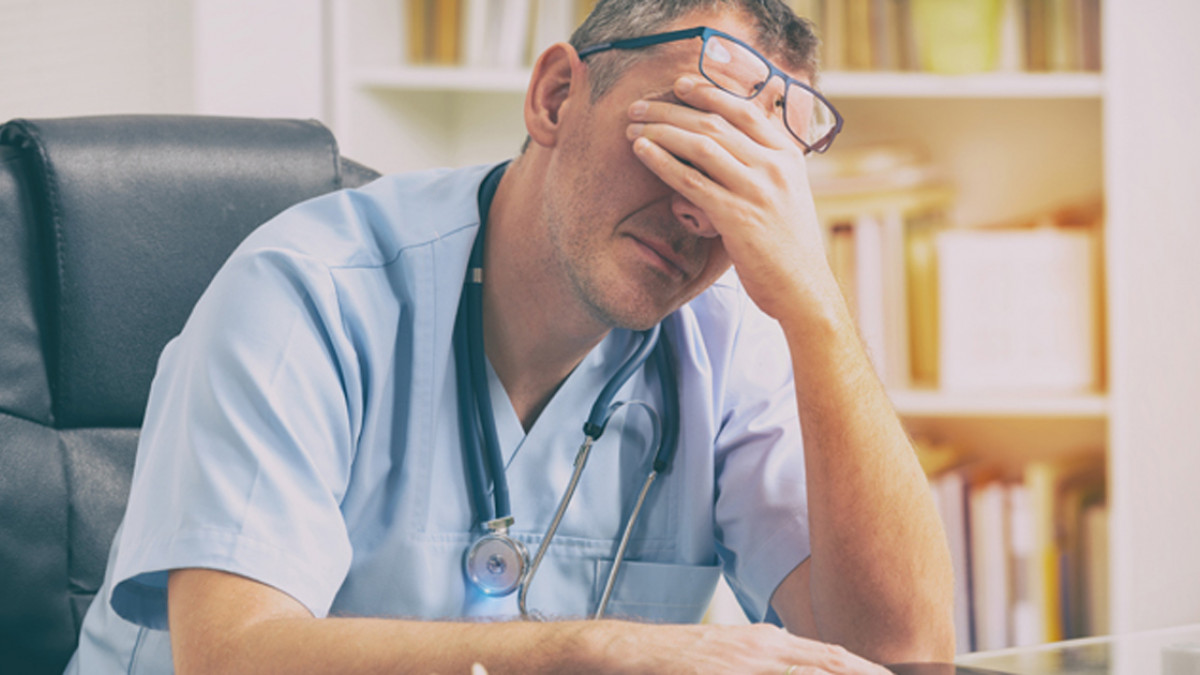 tired physician with head in hand