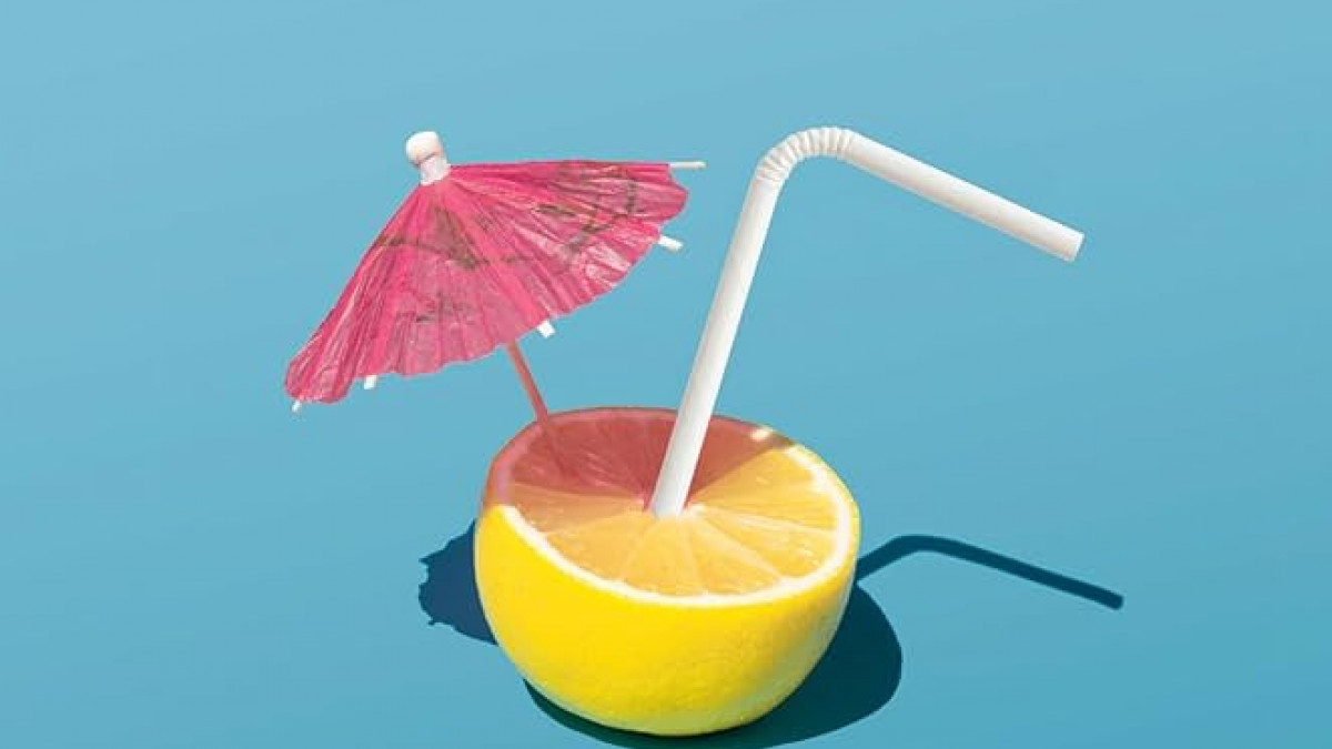 Practical Optimism Cover: A lemon with a straw and a cocktail umbrella sticking out of it